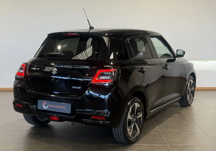 Suzuki Swift 2025 noire vue 3/4 arrière droit, avec feux arrière allumés et jantes alliage distinctives.