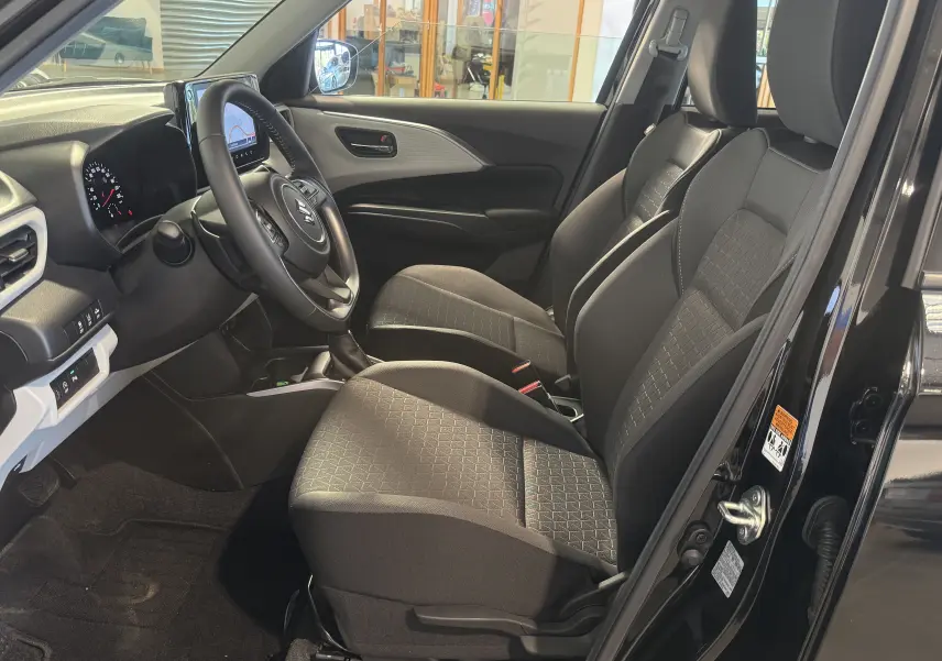 Vue intérieure côté conducteur de la Suzuki Swift noire 2025, montrant sièges tissu et tableau de bord moderne.