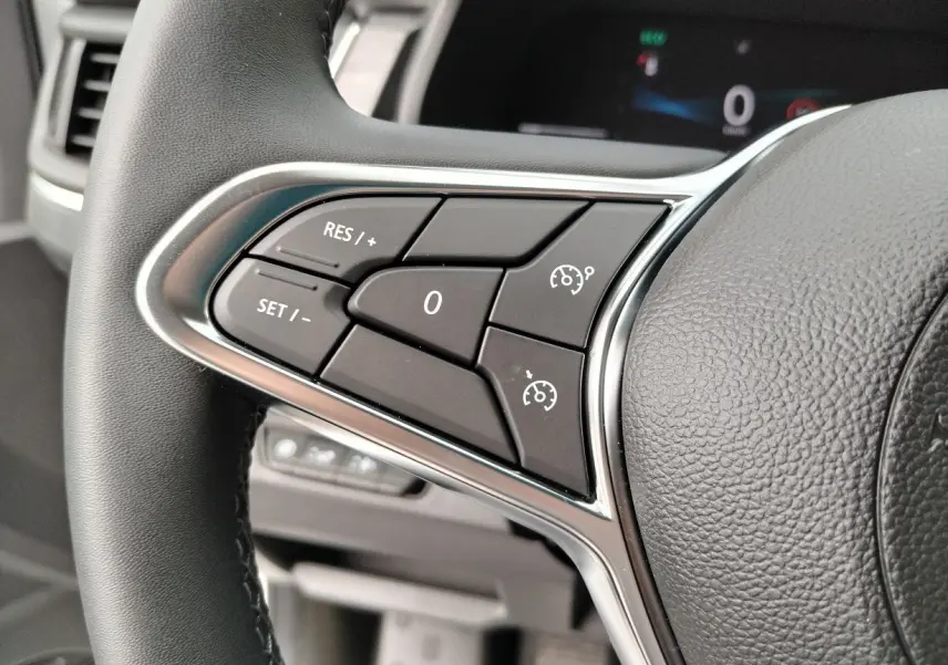 Gros plan sur les commandes de régulateur de vitesse au volant noir du Nissan Primastar blanc 2025.