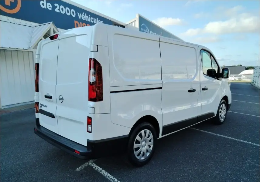 Vue 3/4 arrière droite d'un utilitaire blanc Nissan Primastar 2025 avec portes arrière battantes et jantes tôles.