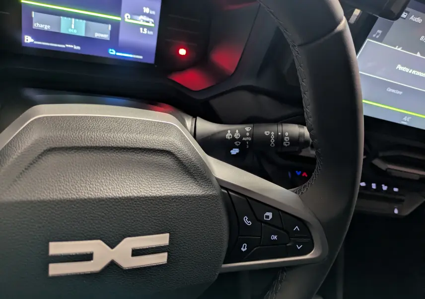 Vue rapprochée du volant noir du Dacia Duster Hybrid 140 Journey 2025 avec commandes intégrées et tableau de bord digital.