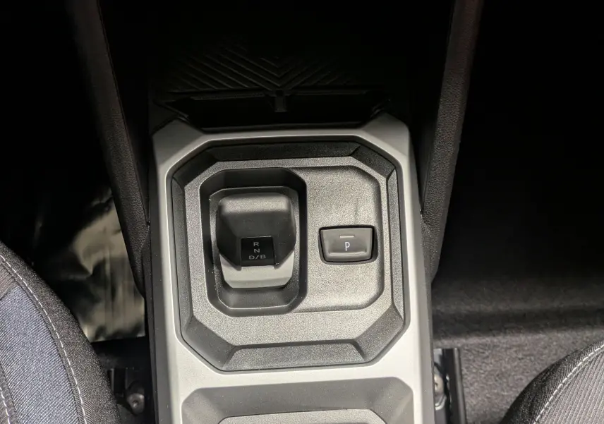 Vue plongeante sur la console centrale du Dacia Duster Hybrid 140 blanc glacier, avec levier de vitesse et commandes.