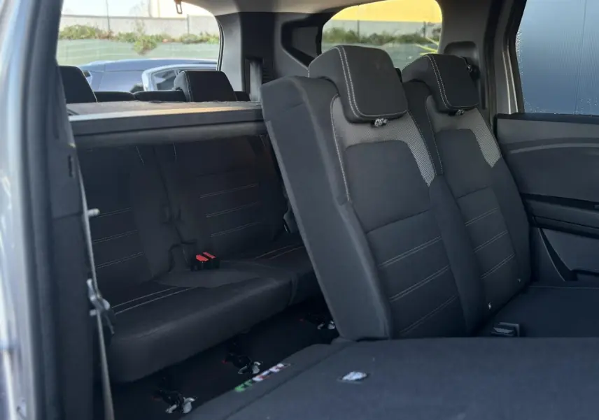 Vue intérieure arrière du Dacia Jogger gris Schiste, montrant les sièges du 2e et 3e rang avec sellerie noire Expression.