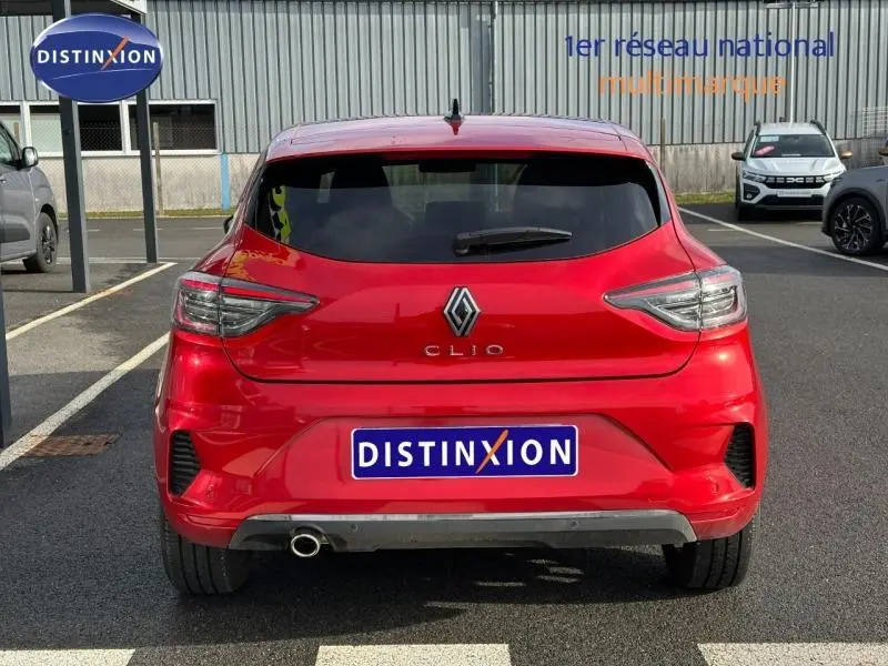 Vue arrière d'une Renault Clio Rouge Flamme 2025, mettant en valeur ses feux LED et le logo central sur un parking extérieur.