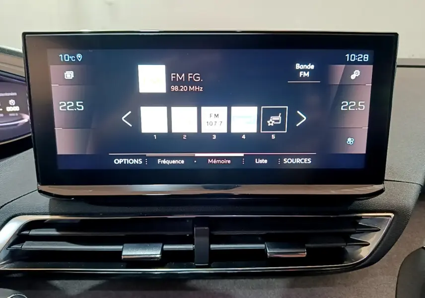 Écran tactile central du tableau de bord du Peugeot 3008 GT 2023, affichant la radio FM et la climatisation digitale.