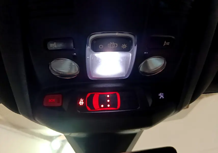 Vue rapprochée du plafonnier intérieur du Peugeot 3008 noir, avec éclairage et boutons SOS et verrouillage activés.