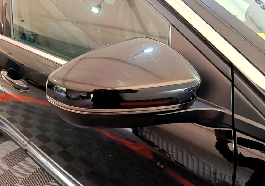 Gros plan sur le rétroviseur côté gauche noir brillant du Peugeot 3008 GT 2023 avec bande chromée fine.