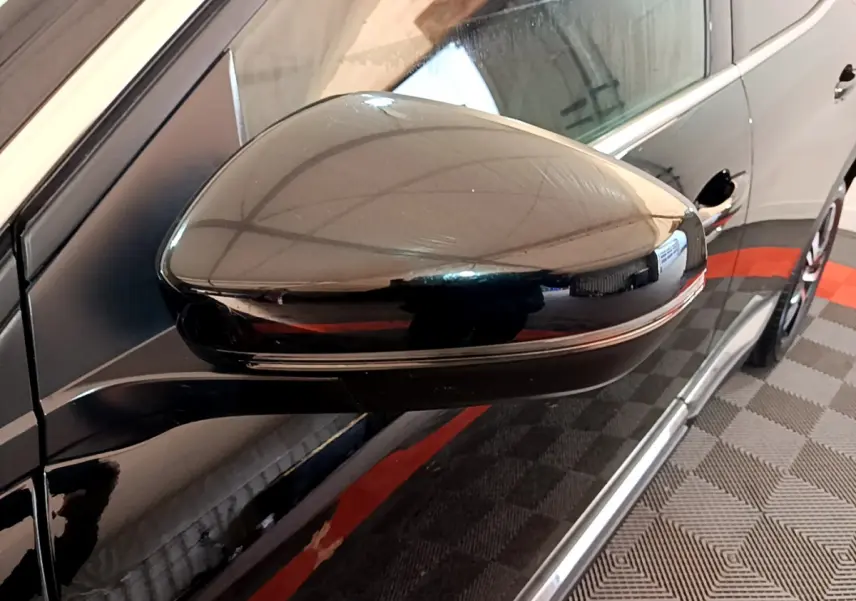Rétroviseur côté gauche noir brillant du Peugeot 3008 2023 GT, avec reflet de l'environnement intérieur.