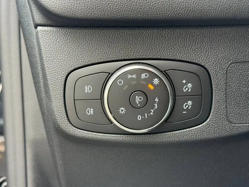 Gros plan sur le sélecteur de réglage des phares du Ford Focus SW 1.0 Ecoboost Titanium 2023, intérieur noir.