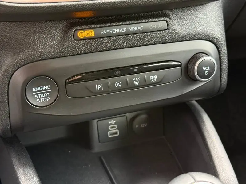Gros plan sur la console centrale noire du Ford Focus SW 1.0 Ecoboost 2023 avec boutons de démarrage et commandes audio.