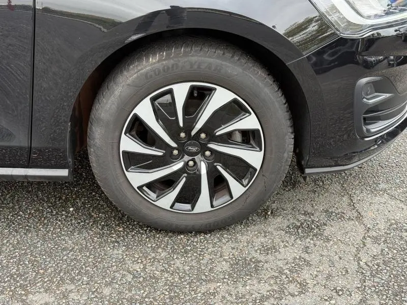 Gros plan sur la roue avant gauche d'une Ford Focus SW 1.0 Ecoboost Titanium noire avec jante alliage bicolore.
