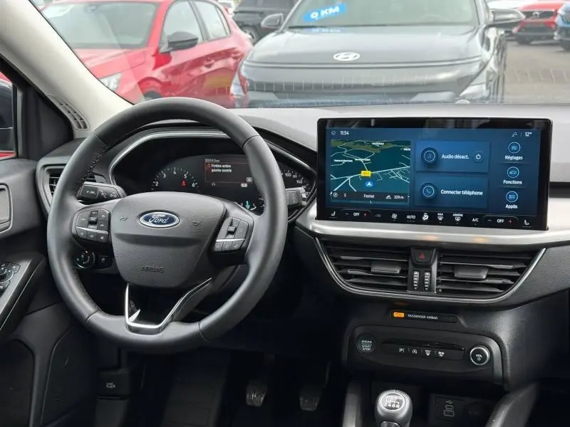 Vue intérieure frontale du tableau de bord et volant de la Ford Focus SW 1.0 Ecoboost Titanium 2023 en Noir Agate métallisé.