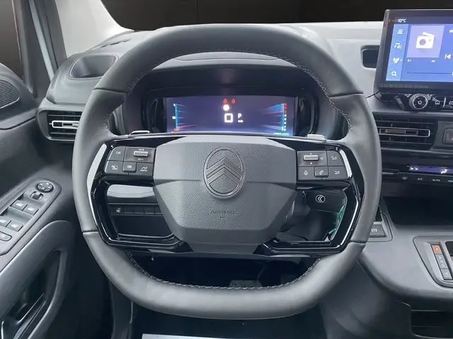 Vue rapprochée du volant cuir multifonctions noir du Citroën Berlingo blanc 2025 avec tableau de bord digital et écran tactile.