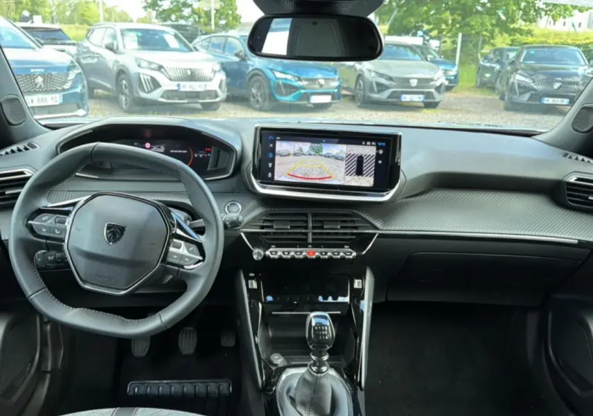 Vue intérieure avant du Peugeot 2008 gris Artense, avec tableau de bord moderne et écran tactile central affichant la caméra de recul.