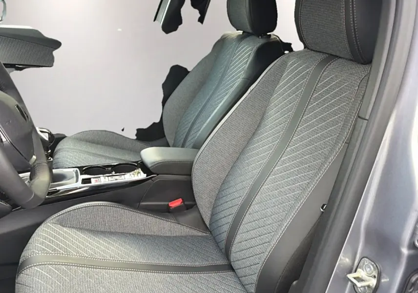 Vue intérieure côté conducteur montrant les sièges en tissu gris embossé du Peugeot 2008 1.2 100 Allure gris Artense.