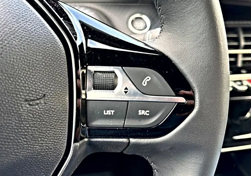 Gros plan sur les commandes noires du volant multifonction du Peugeot 2008 1.2 100 Allure gris Artense.