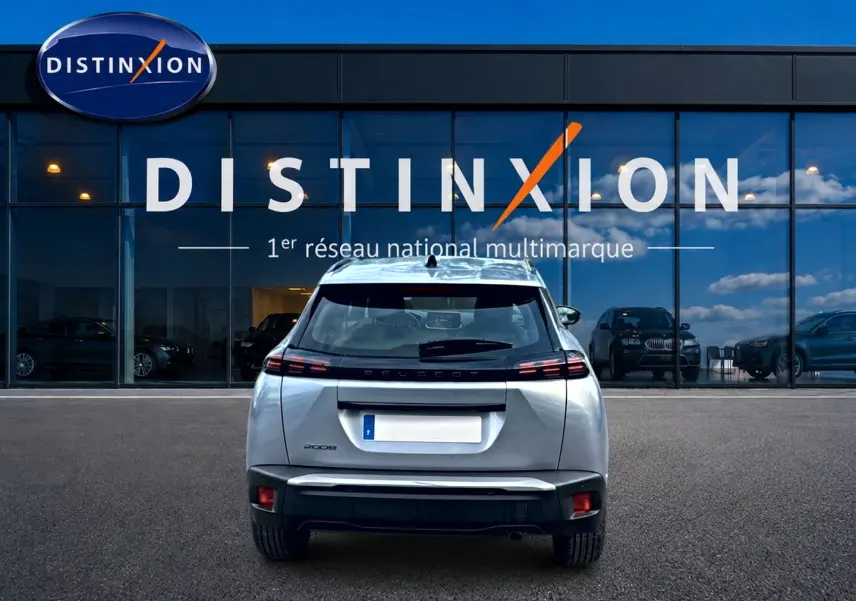 Vue arrière d'un Peugeot 2008 gris artense 2025 garé devant une vitrine avec logo Distinxion.