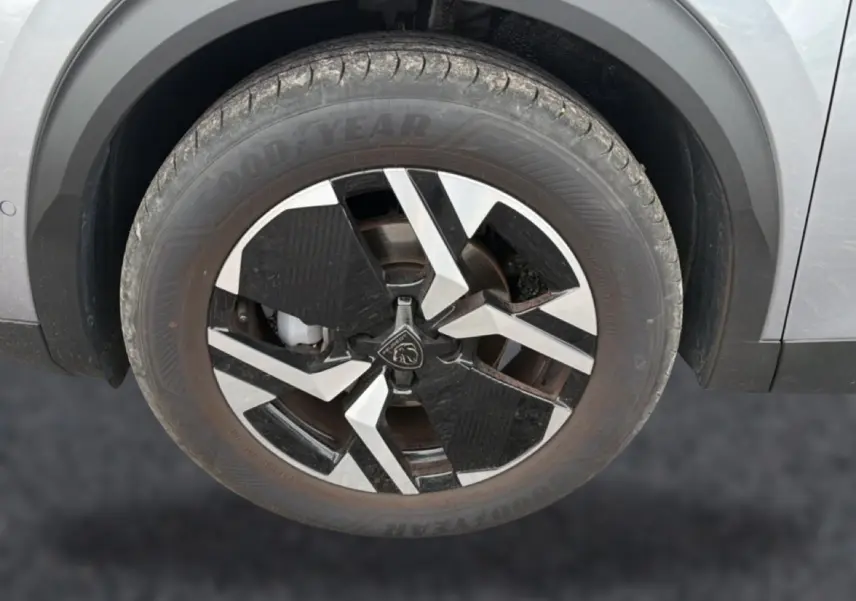 Gros plan sur la roue avant gauche du Peugeot 2008 gris Artense avec jante alu bicolore et logo lion central.