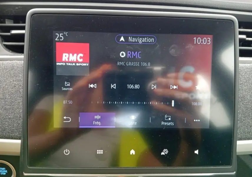 Écran tactile central de la Renault ZOE violet, affichant la radio RMC à 10:03, vue rapprochée de l’intérieur.