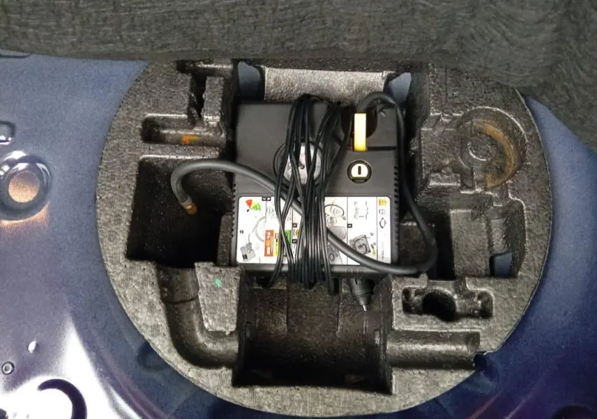 Chargeur et câbles rangés dans le coffre, vue plongeante sur l’espace de rangement en mousse violet de la Renault ZOE électrique 2022.