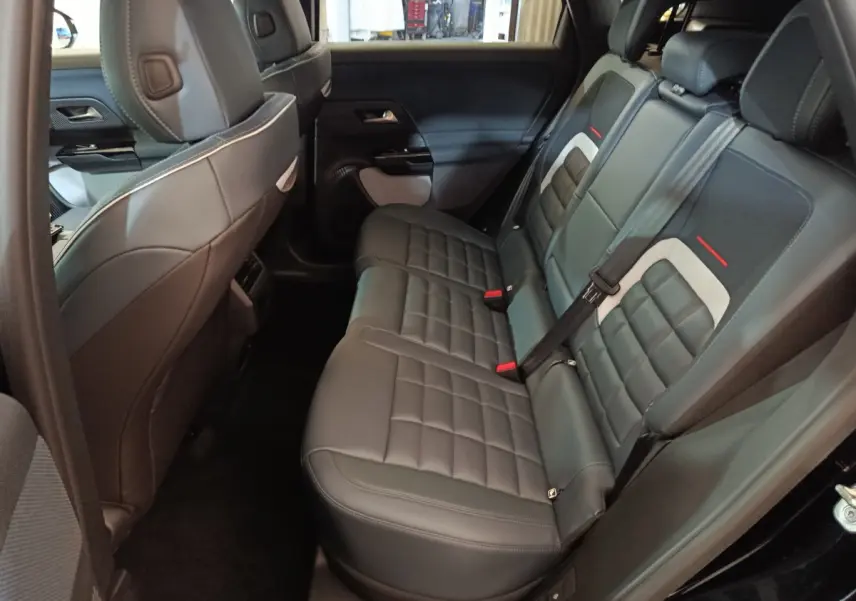 Vue intérieure côté droit des sièges arrière en cuir noir du Citroën C5 Hybride 2026 avec détails gris et rouges.