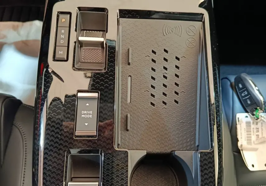 Vue plongeante sur la console centrale noire brillante du Citroën C5 Hybride 2026 avec commandes et recharge sans fil.
