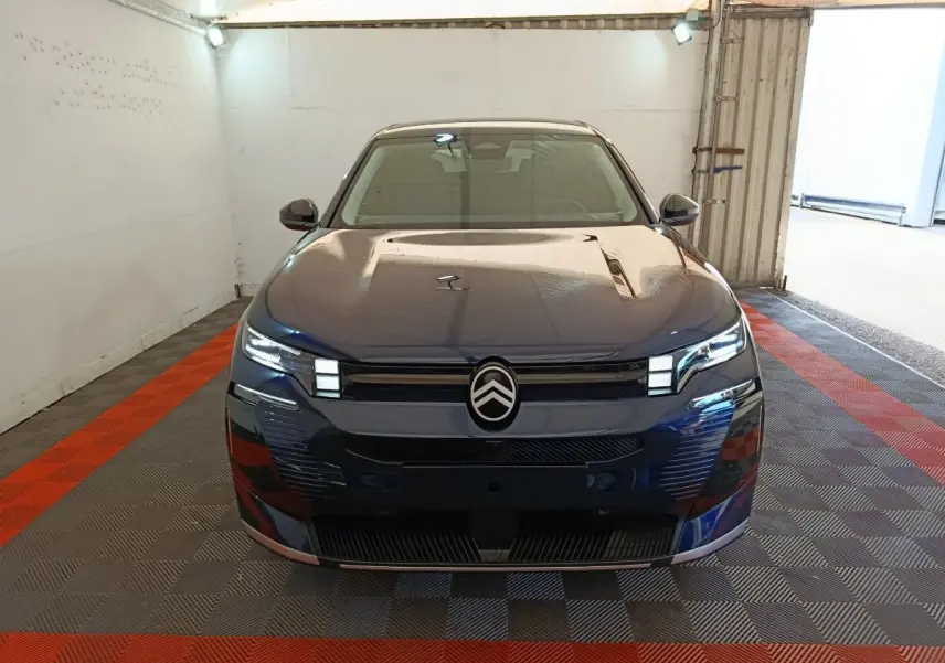 Vue frontale d'une Citroën C5 hybride bleu foncé avec phares LED et logo distinctif au centre de la calandre.