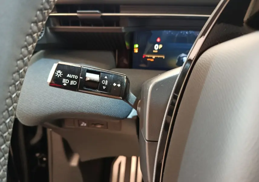 Gros plan sur la commande des feux à gauche du volant dans l’habitacle gris d’une Citroën C5 Hybride bleue 2026.