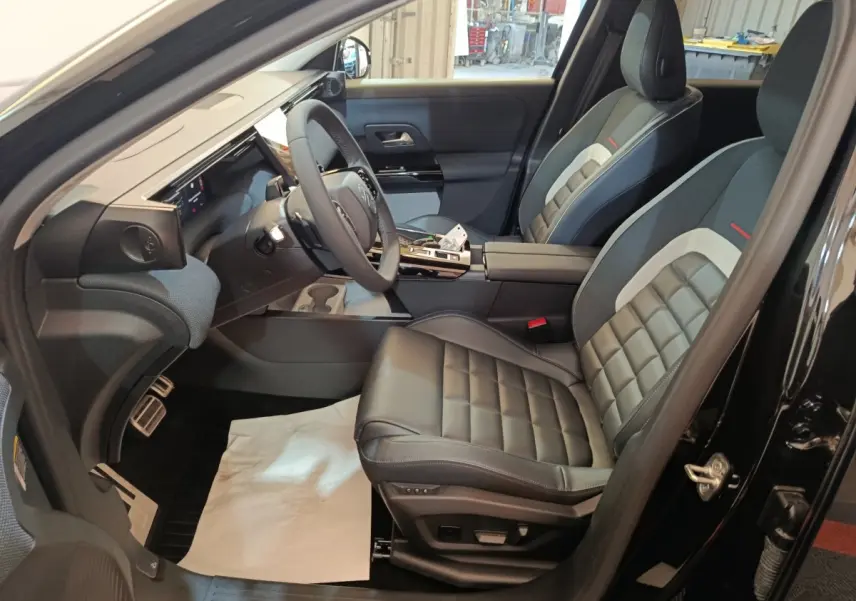 Vue intérieure côté conducteur de la Citroën C5 hybride 2026, sièges cuir noirs et tableau de bord moderne.