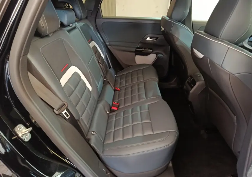Vue côté gauche des sièges arrière en cuir noir avec surpiqûres blanches et détails rouges dans une Citroën C5 Hybride 2026.