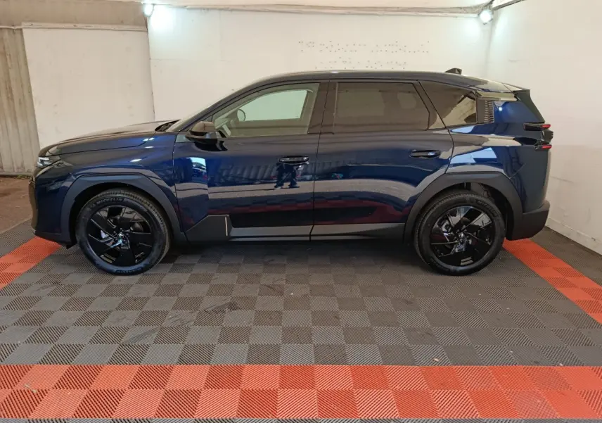Vue latérale droite d’un Citroën C5 hybride bleu foncé avec jantes noires et toit noir dans un garage.