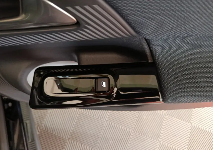 Gros plan sur la commande de lève-vitre côté gauche de la porte intérieure d’une Citroën C5 Hybride bleue 2026.