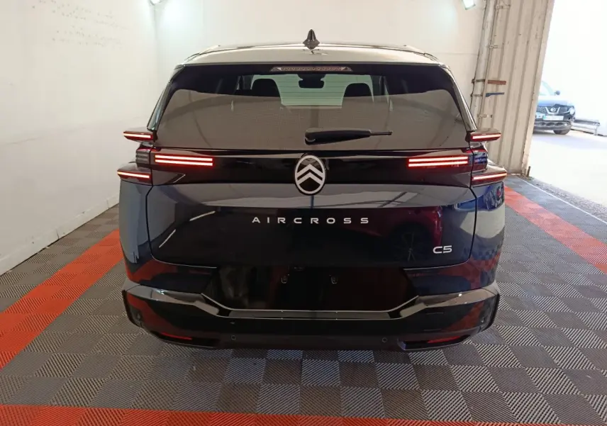 Vue arrière d'une Citroën C5 Aircross bleu foncé avec feux LED horizontaux allumés dans un garage.