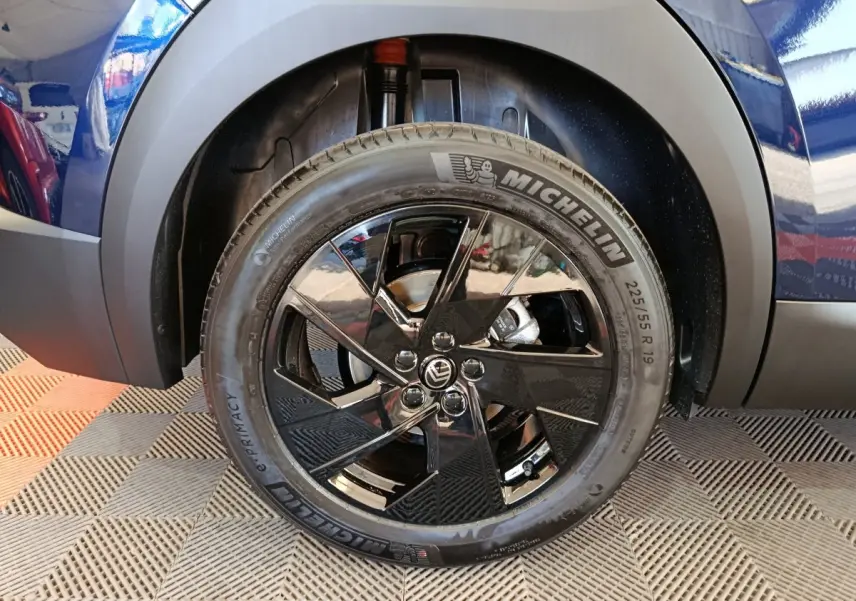 Gros plan sur la roue avant droite bleue d’une Citroën C5 Hybride avec jante noire brillante et pneu Michelin.