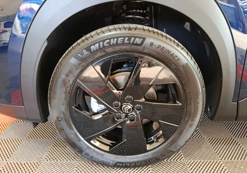 Gros plan sur la roue avant droite d'une Citroën C5 hybride bleu, avec jante noire brillante et pneu Michelin.