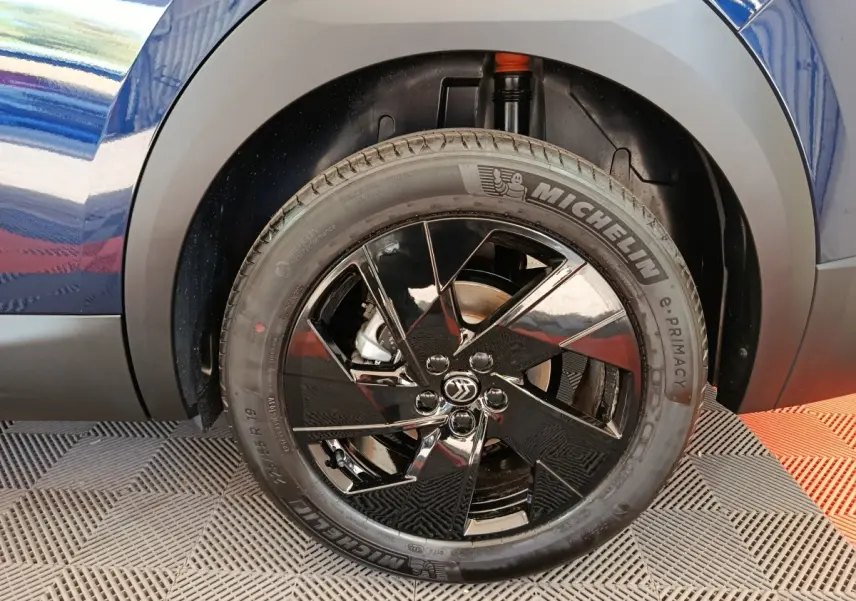 Gros plan sur la roue avant droite noire brillante d'une Citroën C5 Hybride bleu, avec pneu Michelin visible.