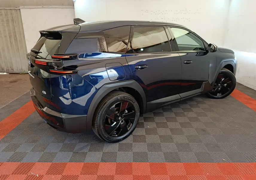 Vue 3/4 arrière droite d'une Citroën C5 hybride bleu foncé avec jantes noires et feux arrière LED distinctifs.