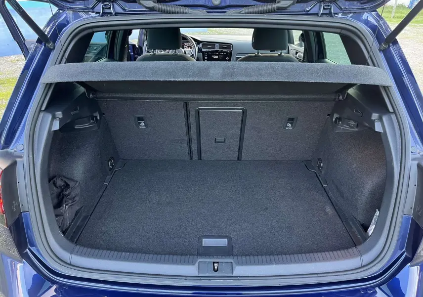 Coffre ouvert d'une Volkswagen Golf VII GTI Performance bleu lapiz metal, vue arrière montrant l'espace de chargement et l'intérieur.