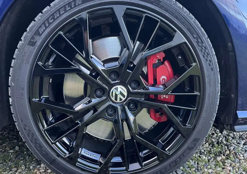 Gros plan sur la roue avant droite d'une Volkswagen Golf GTI Performance bleu lapiz, jante noire et étrier de frein rouge visible.