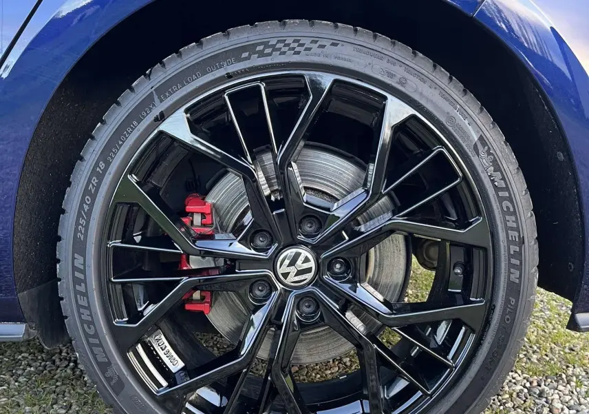 Gros plan sur la roue arrière droite d'une Volkswagen Golf VII bleu lapiz avec jante noire brillante et étrier de frein rouge.