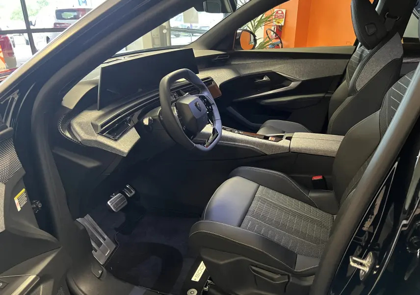 Intérieur avant droit du Peugeot 5008 noir 2025, avec sièges en cuir noir et tableau de bord moderne à écran panoramique.