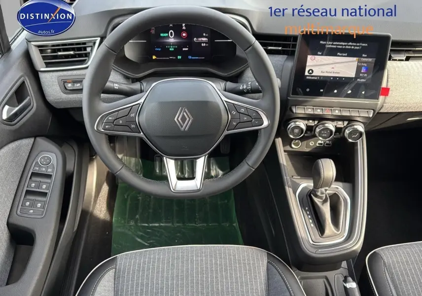 Vue intérieure avant de la Renault Clio V 1.6 e-tech avec tableau de bord numérique et console centrale moderne.