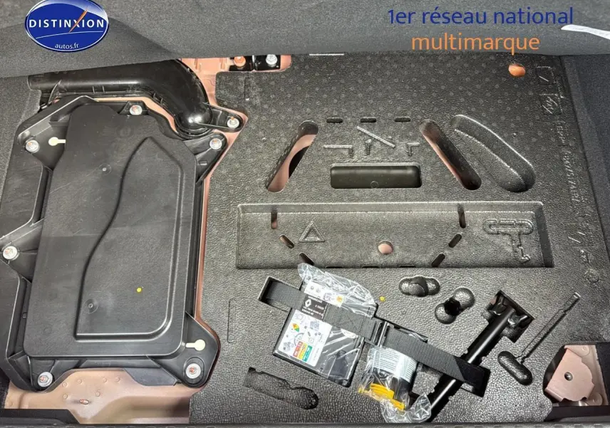 Vue du coffre de la Renault Clio V orange Valencia montrant le rangement sous plancher avec kit de réparation pneus.