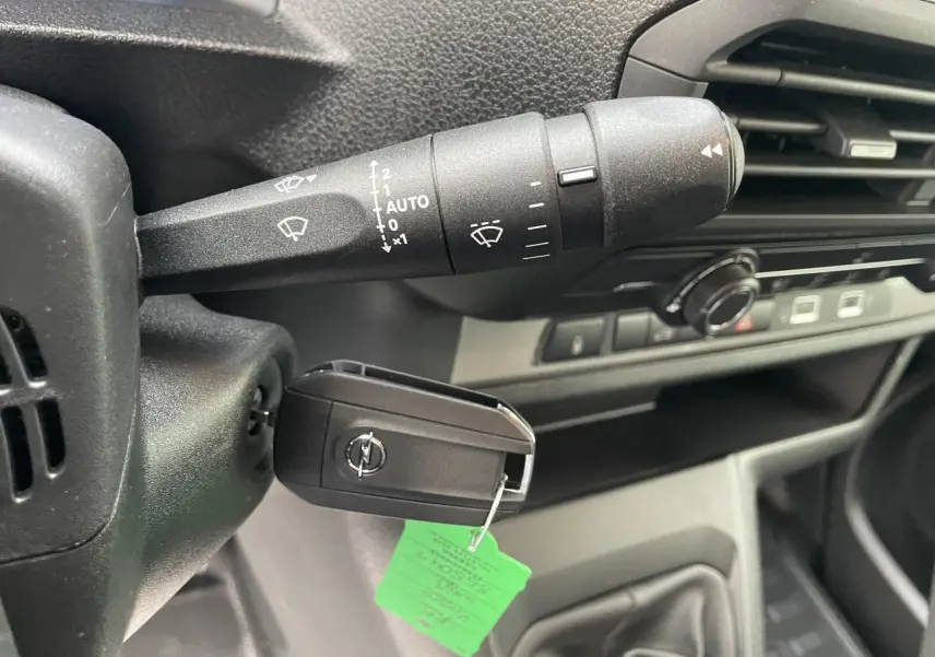 Gros plan intérieur sur la clé Opel insérée à gauche du volant noir avec commandes d'essuie-glace visibles.