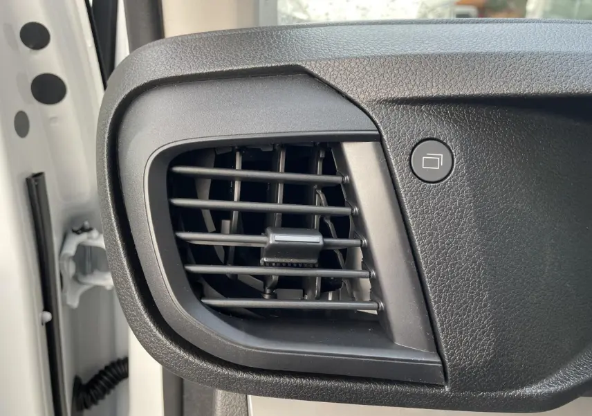 Gros plan sur la grille d'aération noire du tableau de bord côté gauche d'un Opel Vivaro blanc 2024.