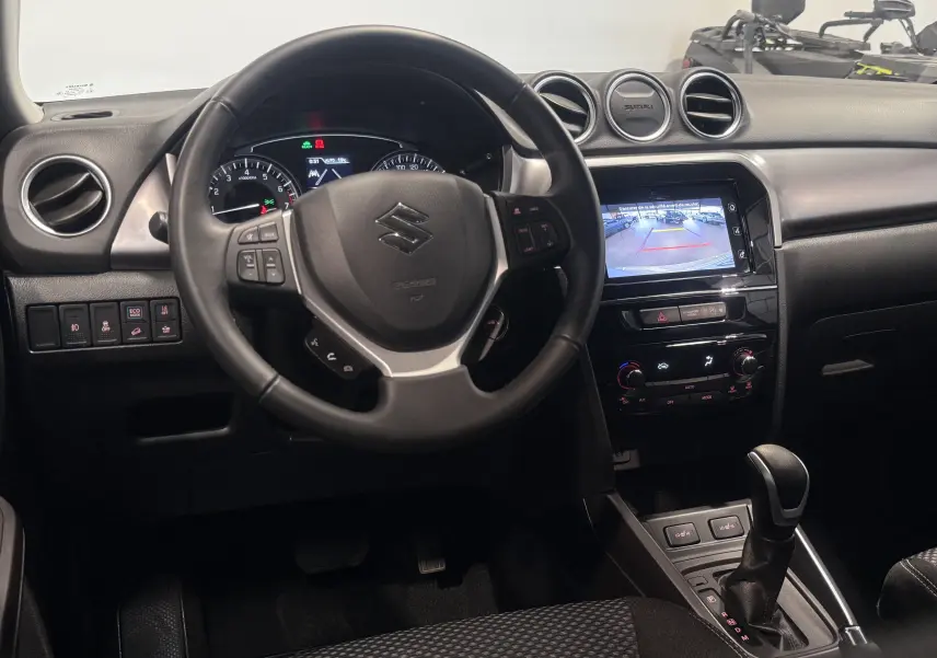 Vue intérieure du tableau de bord du Suzuki Vitara beige 2023, avec volant multifonction et écran tactile affichant la caméra de recul.