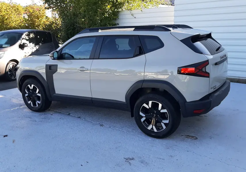 Dacia Duster 2025 couleur sandstone vue de profil côté gauche, avec jantes noires et détails noirs contrastants.