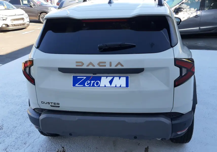 Vue arrière d'un Dacia Duster 2025 couleur Sandstone avec logo DACIA en relief et vitres arrière teintées.