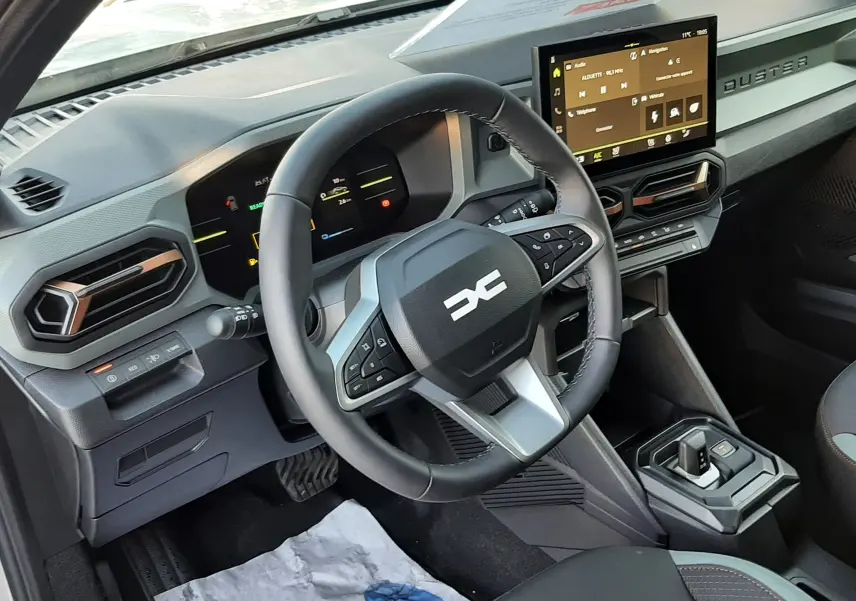 Vue intérieure du tableau de bord du Dacia Duster 2025 avec volant multifonction et écran tactile central.