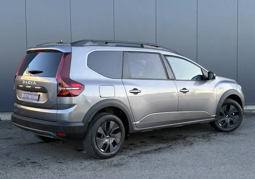 Vue 3/4 arrière droite d'un Dacia Jogger gris schiste avec barres de toit et jantes noires distinctives.